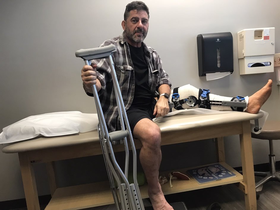 Stu Davidson recovering from patella and quad tendon repair with crutches and knee brace